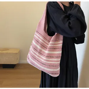 Detailed view of the pink and white striped knitted tote bag, showing shoulder wear and knit texture.