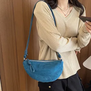 Vue détaillée d'un élégant sac croissant bleu avec une bandoulière nouée unique.