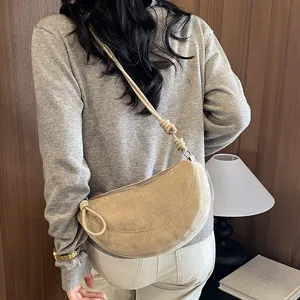 Vue détaillée d'un sac porté épaule croissant en suédine beige avec bandoulière nouée.