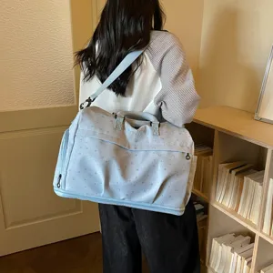 Stylish light blue travel duffel bag with cute star moon pattern and shoulder strap lifestyle.