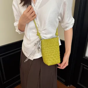 Detailansicht der grünen geflochtenen Ledertasche mit Knotenriemen und schickem Silberanhänger.