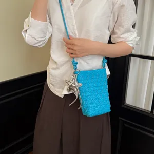 Detailaufnahme der stilvollen blauen geflochtenen Handytasche mit Anhänger für Alltag.