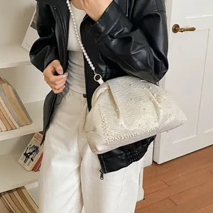 Detailed shot of a stylish pearl shell crossbody bag with metallic texture and chic pearl strap.