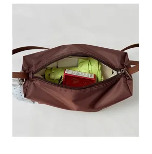 Dettaglio della borsa a spalla in nylon marrone che mostra la capacità interna e la chiusura lampo.