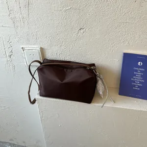 Vista dettagliata di una borsa a tracolla minimalista in nylon marrone scuro con cinturino.