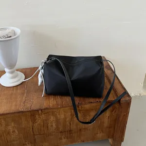 Dettaglio borsa a spalla minimalista in nylon nero, borsa a tracolla a cuscino leggera.