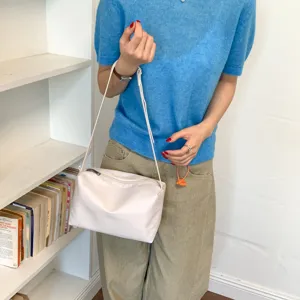 Borsa a tracolla minimalista bianca sotto l'ascella, vista dettagliata della borsa.
