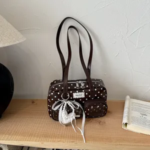 Vue détaillée du sac porté épaule marron à pois avec pendentif cœur et perles élégantes.