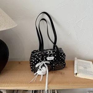 Vue détaillée du sac porté épaule élégant à pois noirs et blancs avec de charmants pendentifs.