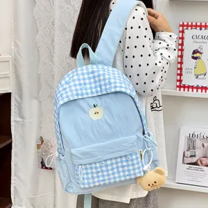 Détail de sac à dos d'écolier à carreaux bleus de style japonais avec broderie de pomme.