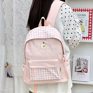 Vue détaillée d'un joli sac à dos rose à carreaux avec broderie de pomme et poches pratiques.