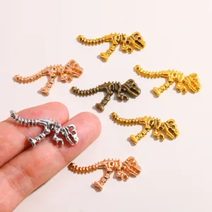 Close up of metal dinosaur skeleton charms in various finishes, perfect for DIY jewelry making.