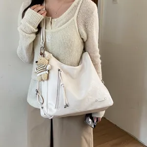 Detail view of the stylish commuter hobo shoulder bag in cream white with a cute bear pendant.