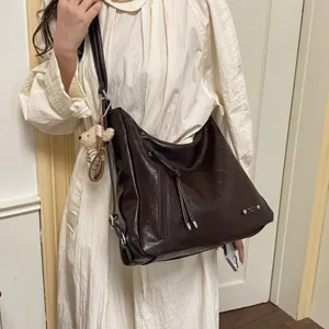 Dark brown slouchy shoulder bag detail, multi-functional crossbody and backpack style with bear.