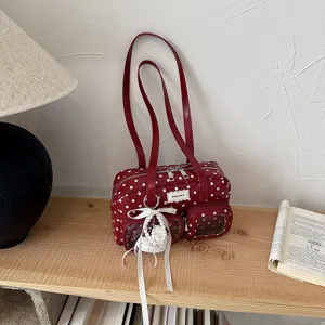 Détail de sac à épaule à pois rouges, avec poche avant transparente, doubles bretelles et nœud.