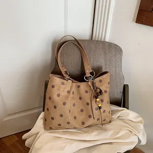 Detailed view of brown polka dot tote shoulder bag showing texture, strap and charm.