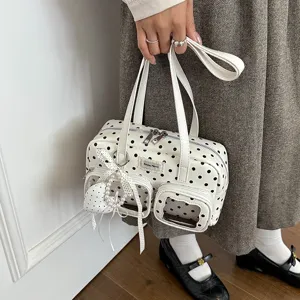 Gros plan sur le sac porté épaule à pois blancs, double poche avant et charm perlé.