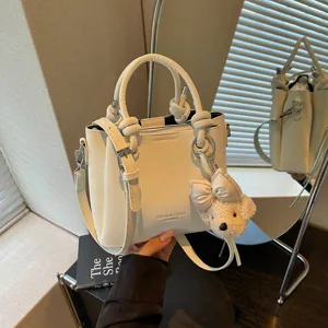 Bolso cubo blanco para mujer de piel sintética PU con colgante de oso y asa elegante.