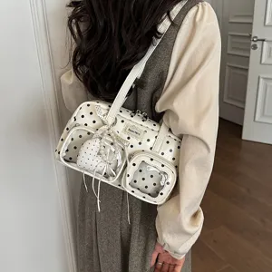 Detailed view of white polka dot shoulder bag, commuter underarm handbag with clear front pockets.