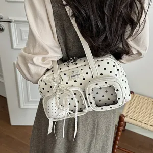 Detail shot of the white polka dot shoulder bag featuring clear front pockets and cute bow.