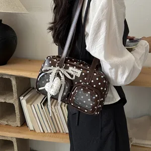Vue de détail d'un sac à bandoulière marron à pois avec poches transparentes et nœud.