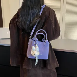 Vista detallada del bolso cubo morado con un tierno colgante de cachorro y correa.