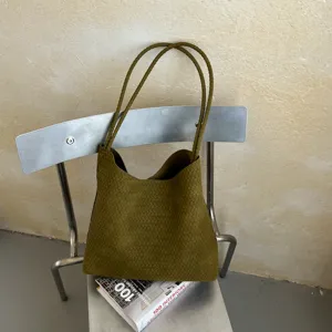 Close-up of olive green woven leather tote bag showing fine texture and modern design.