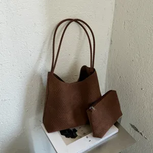 Detailed shot of brown woven leather tote bag with matching pouch on minimalist white setting.