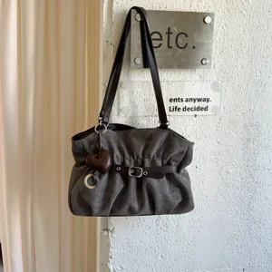 Dettaglio della borsa a spalla in camoscio grigio scuro con design plissettato e ciondolo cuore.