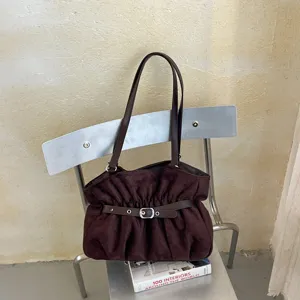 Dettaglio in primo piano della borsa a tracolla arricciata marrone scuro con fibbia chic.