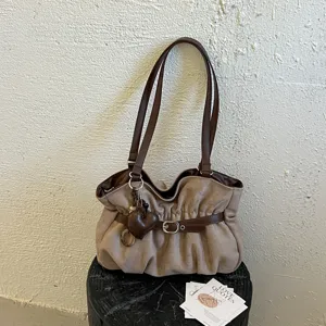 Dettaglio borsa a spalla marrone plissettata con ciondolo a cuore, design casual.