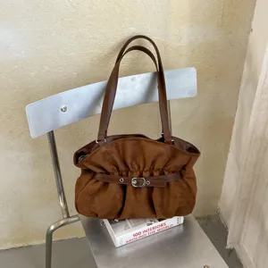 Vista dettagliata della borsa a tracolla in camoscio marrone con fibbia in metallo e design.