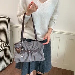 Borsa a tracolla grigia in camoscio con cinturino marrone, fibbia elegante e ciondolo a cuore.