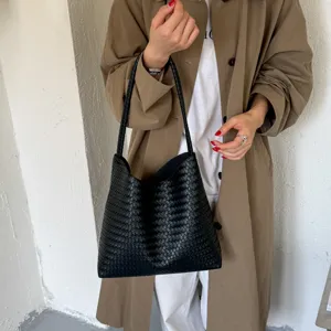 Close up view of a black woven leather tote bag, elegant minimalist design for daily commute.