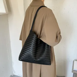 Detailed shot of black woven leather shoulder bag, premium minimalist aesthetic daily tote.