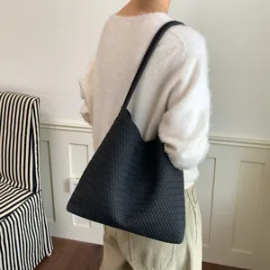 Detail view of the black woven shoulder tote bag worn on shoulder, showcasing premium design.