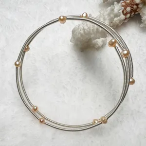 Detail view of multi-layer natural freshwater pearl memory wire bracelet with shiny metallic coils