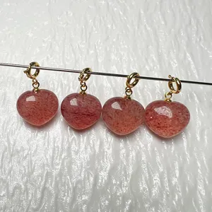 Primer plano del colgante de corazon de cuarzo fresa natural con acabado rojo y cierre dorado.