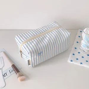 Blue and white striped fabric cosmetic bag with cute bow embroidery and secure zipper closure.
