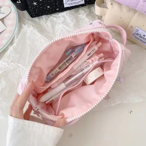 Pink canvas pencil case detail showing large capacity interior, pen slots, and mesh pockets.
