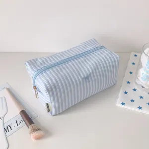 Blue white striped fabric pencil case detail view with cute bow embroidery and zipper.