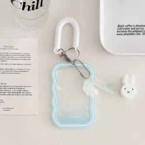 Detailed view of clear wavy card holder keychain with spring lanyard and cute angel wing charm.
