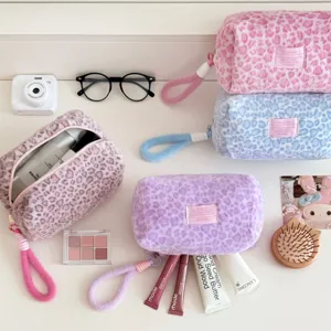 Plush leopard cosmetic bag detail, soft fluffy fabric texture and cute zipper pull design.
