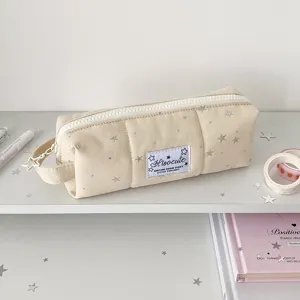 Detail view of the beige canvas pencil case featuring silver stars and star zipper pull.