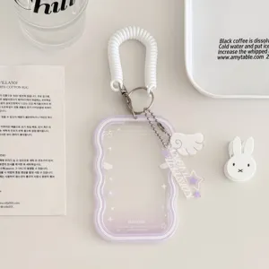 Detailed close-up of a transparent acrylic card holder featuring white spring lanyard and wing pendant.