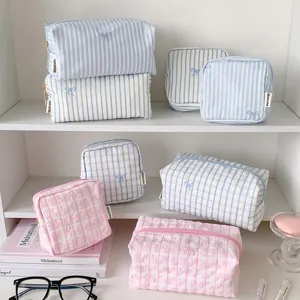 Detailed view of cute striped and plaid cosmetic storage pouches with delicate bow embroidery.