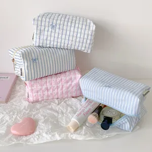 Close-up of striped and plaid storage pencil bags featuring cute bow embroidery and zipper.