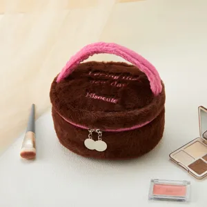 Brown fluffy cosmetic bag with pink handle, cute round makeup pouch for daily travel use.