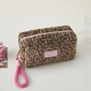 Close-up of fluffy leopard print cosmetic bag detail, soft plush texture with pink wrist strap.