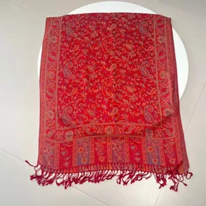 Close-up detail of a vibrant red ethnic paisley jacquard scarf with decorative fringes